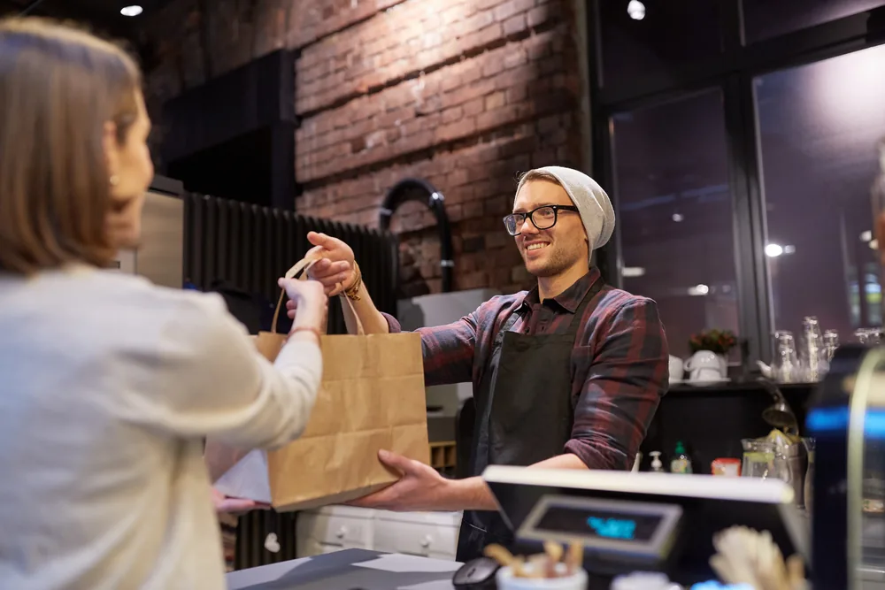 Un commerçant remet une commande click & collect à un client